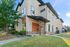Modern apartment exterior with stylish architectural design, featuring large windows, wood accents, and a welcoming entrance framed by lush greenery.