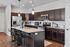 Modern kitchen featuring sleek granite countertops, dark wood cabinetry, stainless steel appliances, and stylish bar seating.