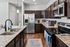Modern kitchen with elegant dark wood cabinets, sleek stainless steel appliances, and granite countertops, illuminated by stylish pendant lighting.