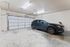 Spacious modern garage with sleek blue SUV, featuring high ceilings and ample lighting.