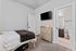 Cozy bedroom featuring a plush bed with a blanket, modern TV, and an elegant wooden dresser leading to an en-suite bathroom.