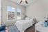 Bright and airy bedroom featuring a cozy bed, elegant decor, and large windows with scenic views.
