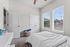 Bright and inviting bedroom with large windows, cozy carpet, and a comfortable bed, offering a serene retreat.