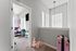 Inviting hallway leading to a cozy bedroom with soft carpet, abundant natural light from large windows, and charming decor elements.