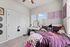 Charming bedroom with a cozy bed, elegant vanity, and bright natural light streaming through large windows, creating a welcoming and tranquil atmosphere.