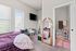 Cozy bedroom with natural light, featuring a stylish wall mirror, TV, and an en-suite bathroom with elegant decor.