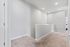 Bright and inviting hallway with soft carpeting and modern recessed lighting, leading to a room with natural light.
