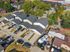 Modern townhouses with sleek roofs and driveways in a vibrant neighborhood surrounded by lush green trees.