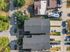 Aerial view of a modern apartment complex with ample parking and surrounding greenery in a quiet neighborhood.