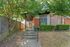 Charming apartment entrance with modern design, lush greenery, and inviting walkway.