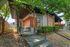 Charming modern bungalow featuring sleek wooden accents, lush greenery, and a welcoming entrance with stylish planters.
