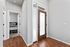 Inviting entryway with elegant wood flooring, complemented by a modern wooden front door with frosted glass, leading to a cozy bedroom.