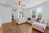 Elegant living room with chic sectional sofa, plush cushions, and stylish ceiling fan, featuring abundant natural light pouring through large windows on beautiful hardwood floors.
