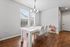 Bright dining area with elegant white table, stylish chairs, chic chandelier, and cozy natural light.