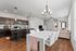 Charming open-concept living space featuring a modern kitchen with dark wood cabinets, elegant dining area, and a cozy sitting room with ample natural light.