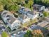 Charming residential community with modern two-story houses, surrounded by lush greenery and ample parking space.