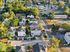 Aerial view of serene suburban neighborhood with modern homes, lush greenery, and ample parking.
