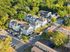 Aerial view of a serene residential neighborhood featuring modern townhouses surrounded by lush greenery and ample parking space.
