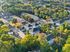 Scenic aerial view of a charming suburban neighborhood surrounded by lush greenery, showcasing modern townhouses and inviting streets.