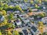 Charming aerial view of a peaceful residential neighborhood showcasing modern homes amidst lush green trees and well-maintained streets.