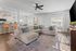 Bright and inviting living room with modern kitchen, featuring a cozy beige sectional, elegant hardwood floors, and abundant natural light.