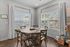 Bright dining nook with large windows, rustic wooden table, and elegant chairs, perfect for enjoying meals in natural light.