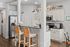 Charming kitchen with sleek black countertops, stainless steel appliances, and cozy bar seating under pendant lighting.
