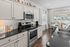 Elegant kitchen with modern stainless steel appliances, dark granite countertops, and crisp white cabinetry, featuring a cozy dining area with large, sunlit windows.