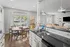 Bright, open-concept kitchen and dining area featuring elegant black granite countertops, cozy wooden dining table, and modern lighting fixtures, exuding warmth and sophistication.