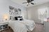 Inviting bedroom with elegant decor, featuring plush bedding, charming artwork, and a warm ambiance.