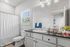 Bright and modern bathroom featuring a sleek black countertop, spacious mirror, and elegant fixtures, with abundant natural light from the window.