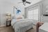 Elegant bedroom with modern decor, featuring a plush white bed, abstract art, and ample natural light from a large window.