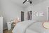 Bright and cozy bedroom featuring elegant decor, a comfortable bed, and a stylish workspace under a modern ceiling fan.