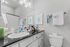 Elegant bathroom boasting a modern design with a sleek black countertop, stylish vanity mirror, and chic wall art for a contemporary touch.