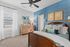 Charming bedroom with elegant blue accent wall, cozy bed, stylish decor, and ample natural light.