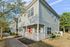 Charming duplex with inviting front porch and vibrant red door, nestled in a peaceful neighborhood surrounded by lush greenery.