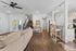 Charming open-plan living area with elegant wooden flooring, modern kitchen with bar seating, and cozy lounge with plush sofa, leading to a bright outdoor patio.