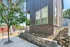 Modern apartment exterior showcasing a sleek design with a stylish mix of brick and siding, surrounded by landscaped rocks and lush greenery on a sunny day.