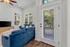 Bright living room featuring a plush blue sectional, large windows with serene views, and elegant decor.