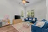 Cozy living room featuring a plush blue sofa, elegant coffee table, and charming decor, enhanced by natural light from large windows.