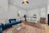 Modern open-plan living area with elegant blue sofa, stylish kitchen island seating, and vibrant area rug.