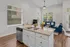 Bright open-concept living room and kitchen with elegant granite countertops and modern appliances, complemented by cozy blue seating and abundant natural light.