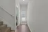 Bright and inviting hallway with modern wood flooring and elegant white walls, leading to a staircase and a door with sleek blinds.