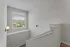 Bright apartment stairway with large window offering scenic views and modern wall sconces.