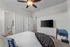 Inviting bedroom with chic white furniture, a sleek ceiling fan, and an ensuite bathroom, perfect for cozy living.