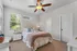 Bright and cozy bedroom with plush queen bed, stylish ceiling fan, and charming natural lighting.