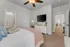 Inviting bedroom featuring plush bedding, modern ceiling fan, and a sleek wall-mounted TV, offering comfort and style.