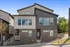 Modern two-story townhouse with a stylish facade, featuring large windows and contrasting brick and siding design, nestled in a serene neighborhood.