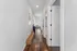 Bright hallway with elegant hardwood floors leading to a sunlit living area, showcasing modern architecture and inviting decor.