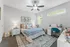 Brightly lit bedroom with chic decor, plush bed, and functional workspace in a cozy apartment setting.